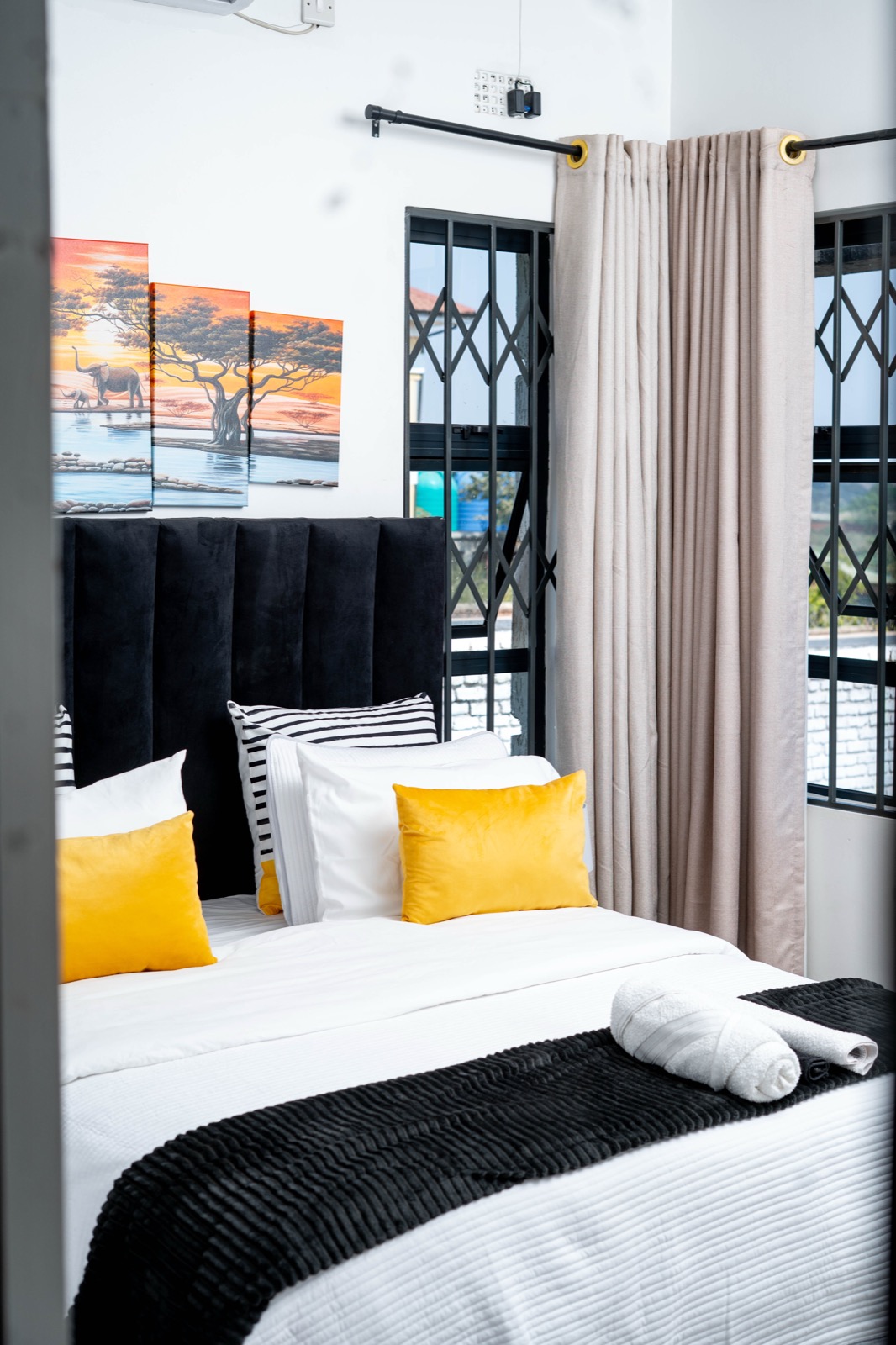 Ensuite bedroom with mustard pillows and elephant art at Nichi Guesthouses