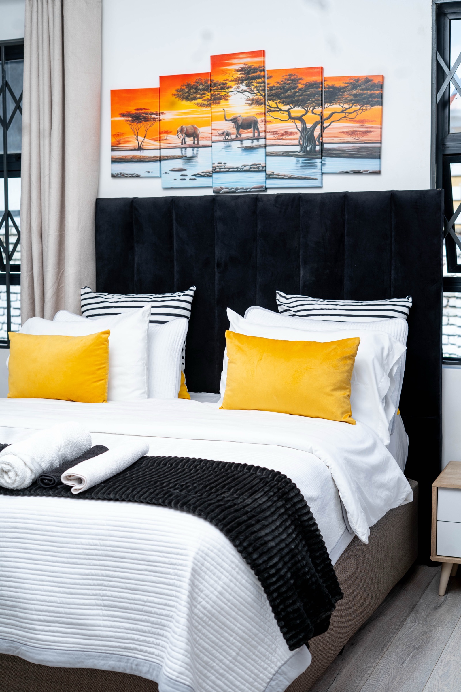 Ensuite bedroom at Nichi Guesthouses with elephant-themed wall art and mustard pillows
